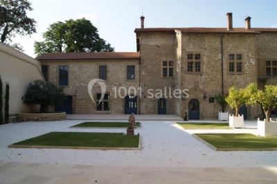 Allée éclairée par des lampes au sol, bordée d'arbres et menant à une entrée illuminée dans l'obscurité.