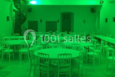 Allée éclairée par des lampes au sol, bordée d'arbres et menant à une entrée illuminée dans l'obscurité.