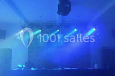 Allée éclairée par des lampes au sol, bordée d'arbres et menant à une entrée illuminée dans l'obscurité.