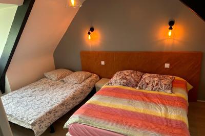 Miniature Location salle Rostrenen (Côtes-d'Armor) - Domaine Un Jour Parfait #19 Chambre moderne avec mur vert, lit double décoré de coussins, luminaires muraux et tapis clair au sol.