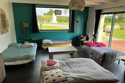 Miniature Location salle Rostrenen (Côtes-d'Armor) - Domaine Un Jour Parfait #12 Chambre moderne avec mur vert, lit double décoré de coussins, luminaires muraux et tapis clair au sol.