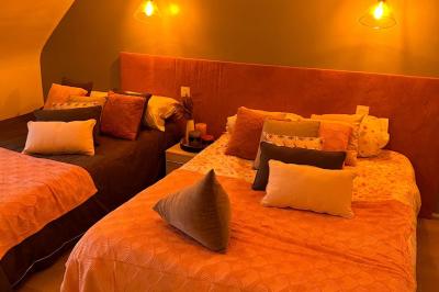 Miniature Location salle Rostrenen (Côtes-d'Armor) - Domaine Un Jour Parfait #18 Chambre moderne avec mur vert, lit double décoré de coussins, luminaires muraux et tapis clair au sol.