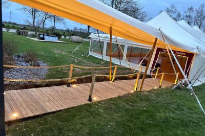 Miniature Location salle Rostrenen (Côtes-d'Armor) - Domaine Un Jour Parfait #14 Chambre moderne avec mur vert, lit double décoré de coussins, luminaires muraux et tapis clair au sol.