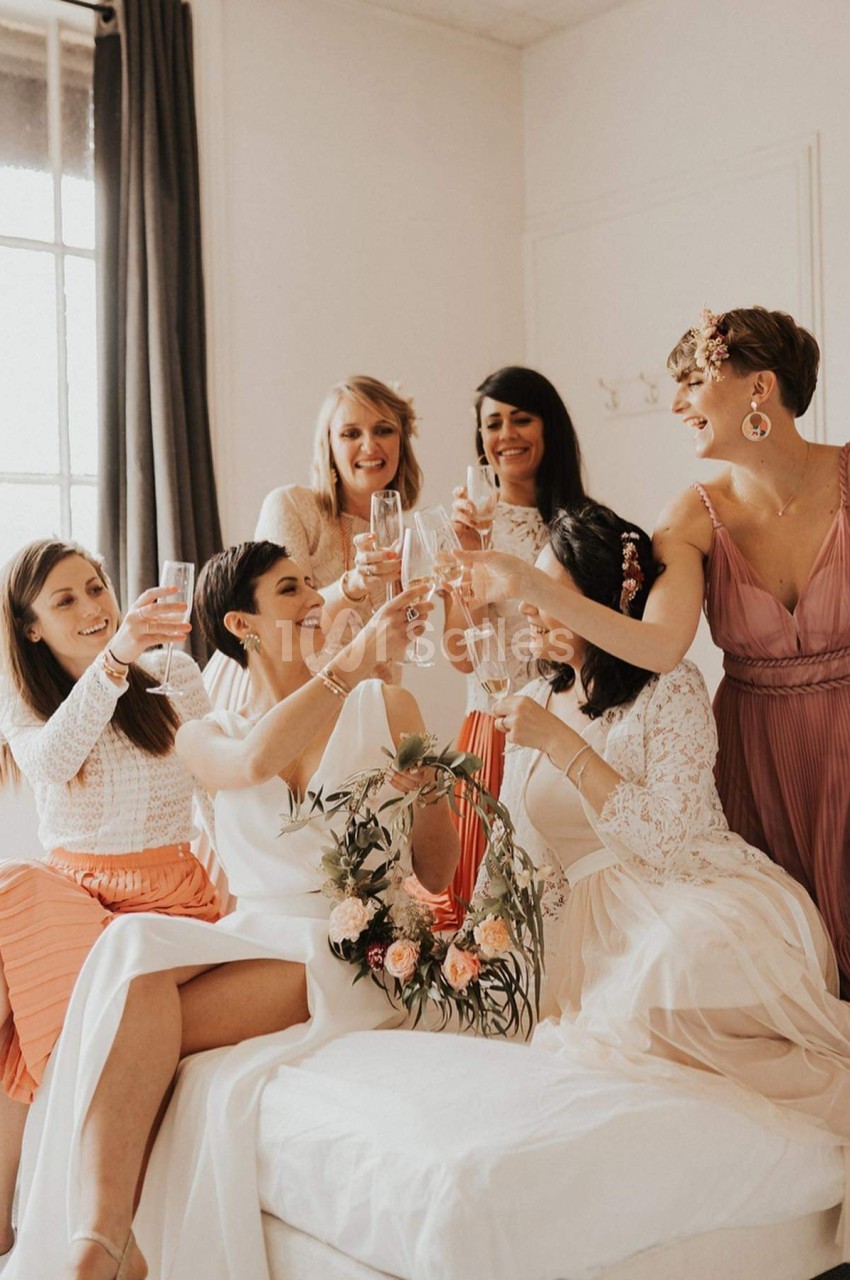 Un groupe de femmes souriantes trinquent avec des verres de champagne dans une pièce lumineuse.