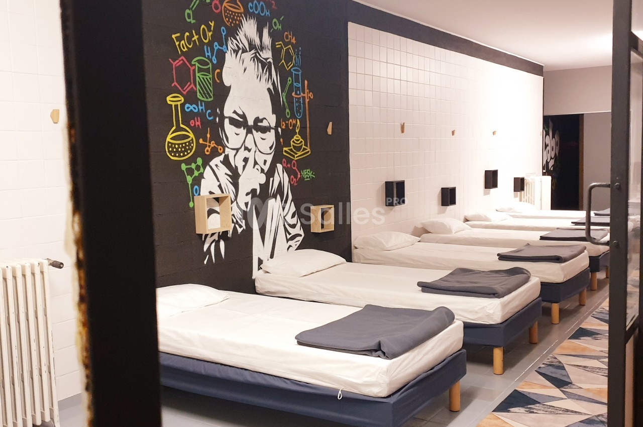 Dortoir moderne avec lits alignés, mur décoré d'une fresque colorée représentant un scientifique pensif.