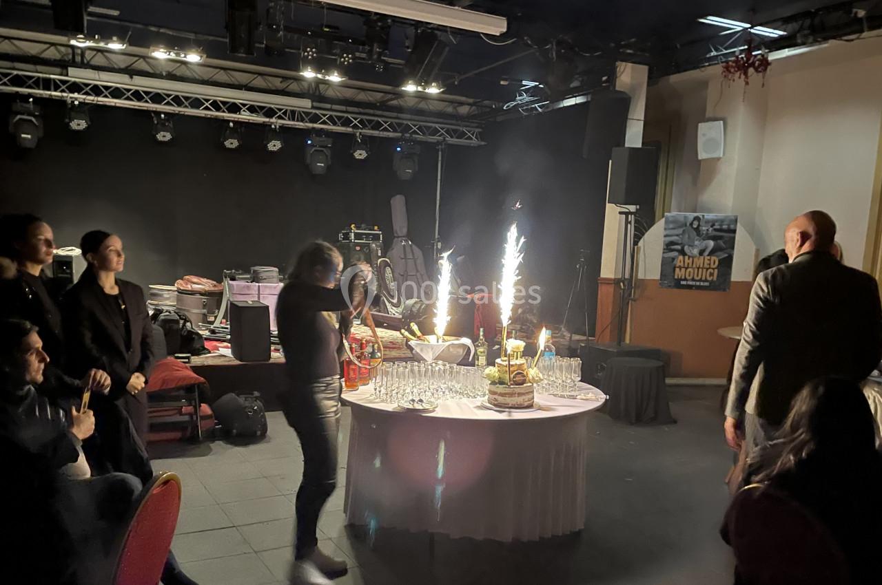 Des personnes rassemblées autour d'une table avec un gâteau décoré de cierges magiques dans une salle sombre.