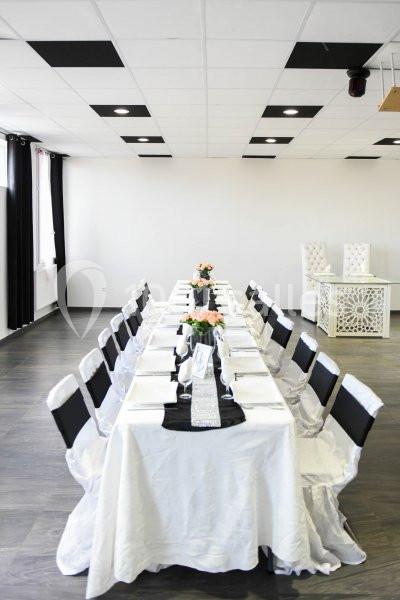 Location salle Hénin-Beaumont (Pas-de-Calais) - Team Square Events #6 Salle lumineuse avec une grande table rectangulaire dressée pour un repas, décorée de nappes blanches et de fleurs.