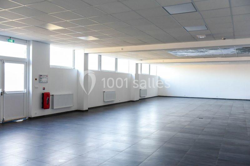 Location salle Hénin-Beaumont (Pas-de-Calais) - Team Square Events #7 Salle vide avec sol en carrelage gris, murs blancs, grandes fenêtres laissant entrer la lumière naturelle.