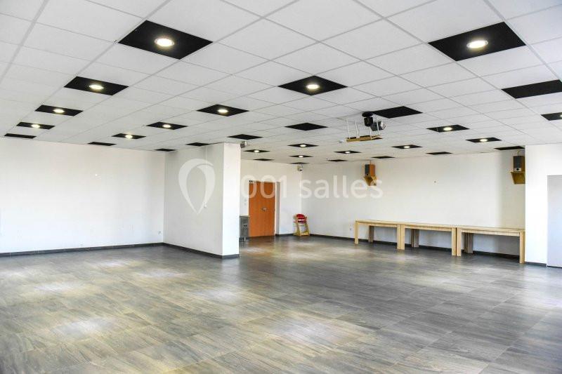 Location salle Hénin-Beaumont (Pas-de-Calais) - Team Square Events #5 Salle vide avec sol en parquet, murs blancs, plafond à dalles avec éclairage intégré et quelques tables en bois.