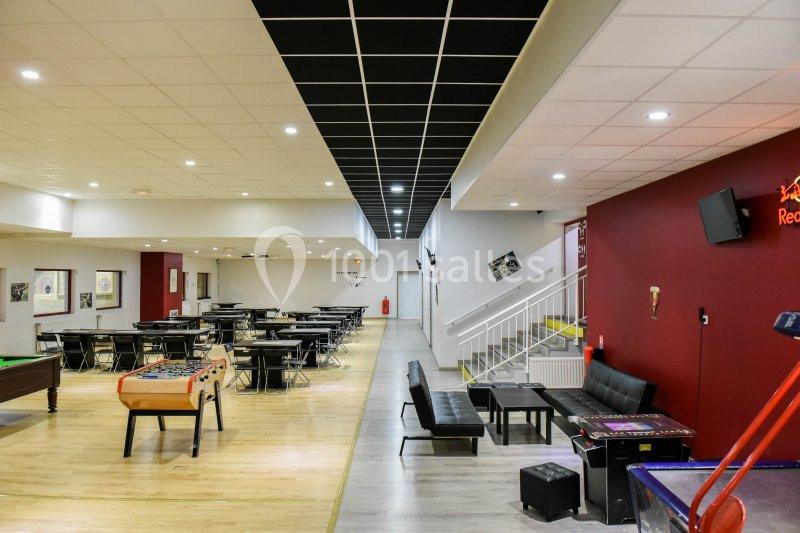 Location salle Hénin-Beaumont (Pas-de-Calais) - Team Square Events #14 Salle de loisirs avec tables de billard, baby-foot, canapés noirs et murs rouges dans un espace lumineux.