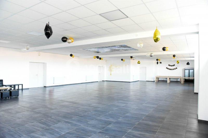 Salle spacieuse avec sol en carrelage sombre, murs blancs et décorations suspendues en noir et or.