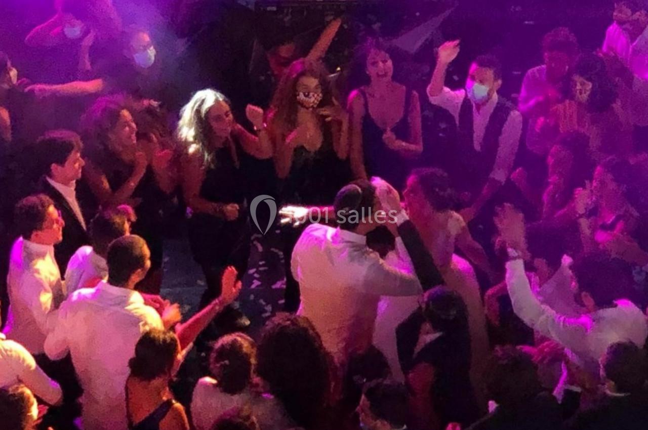 Groupe de personnes dansant et célébrant sur une piste éclairée par des lumières colorées.