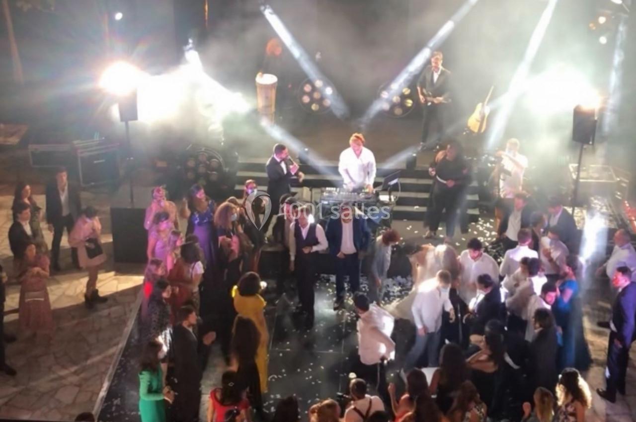 Groupe de personnes dansant sur une piste éclairée par des projecteurs lors d'une fête en plein air avec un groupe en…