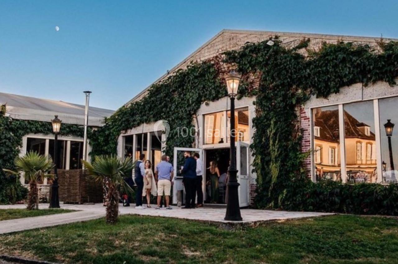 Bâtiment recouvert de lierre avec de grandes fenêtres, des lampadaires et un groupe de personnes à l'entrée.