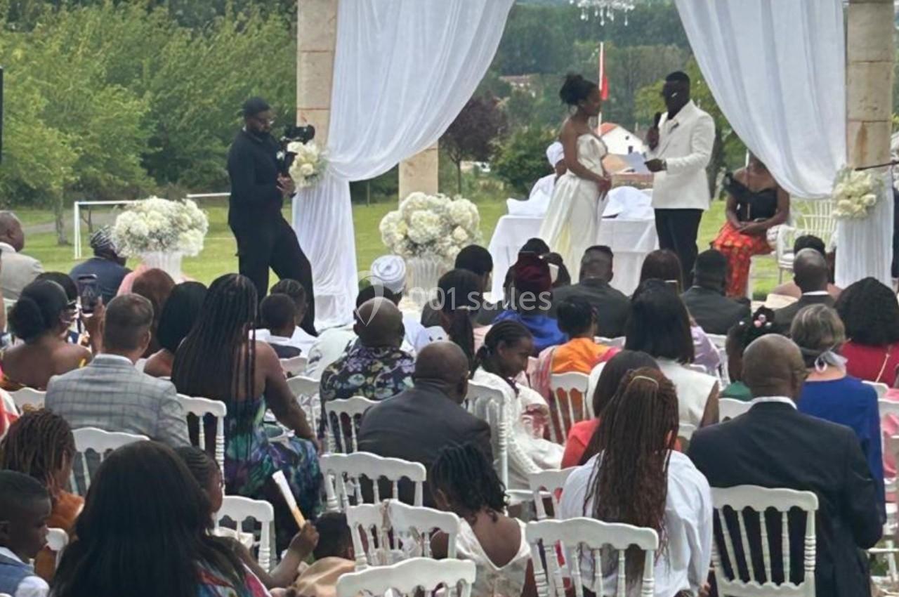 Cérémonie de mariage en plein air avec des invités assis, un couple échangeant ses vœux devant un officiant.