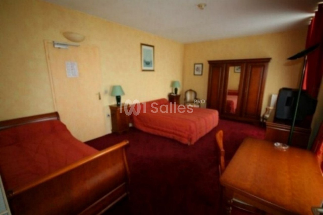 Chambre d'hôtel avec deux lits, un bureau, une armoire en bois, des lampes et un sol recouvert de moquette rouge.
