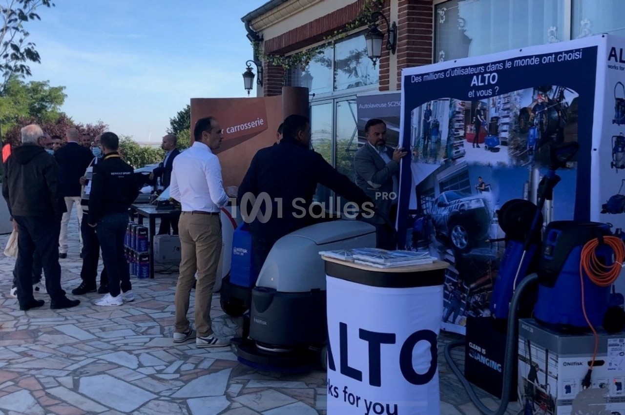 Des personnes discutent autour de stands présentant des équipements de nettoyage professionnel en extérieur.