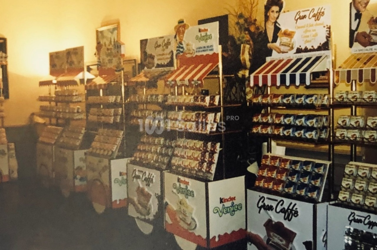 Présentoirs de produits alimentaires avec emballages colorés et affiches promotionnelles dans un espace intérieur éclairé.