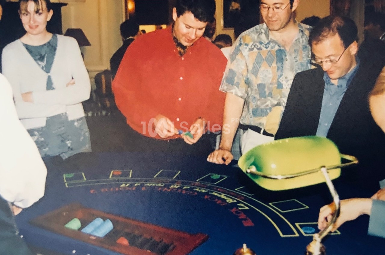 Des personnes jouent au blackjack autour d'une table de casino, observées par un croupier.