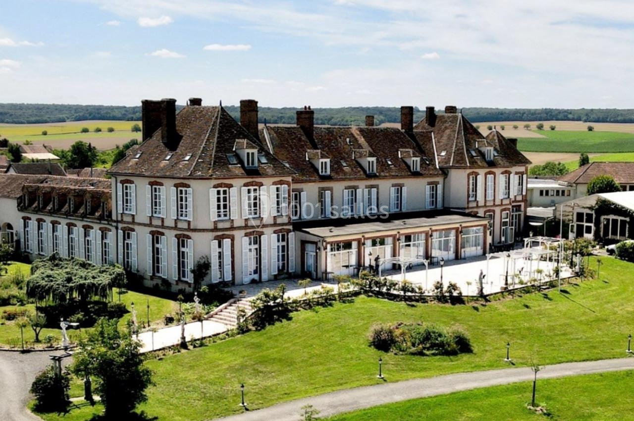 Vue aérienne d'un grand bâtiment historique entouré de jardins verdoyants et de paysages champêtres.