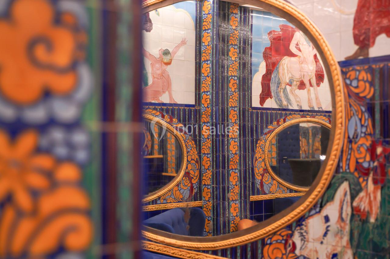 Miroirs ronds dorés reflétant des carreaux colorés ornés de motifs et illustrations dans un décor vibrant.