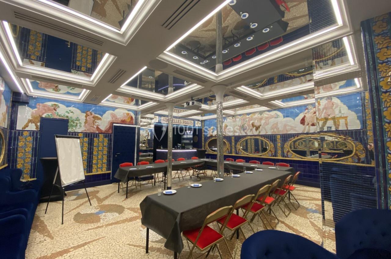 Location salle Paris 2 (Paris) - Aux Belles Poules #10 Salle de réunion élégante avec tables en U, chaises rouges, fresques murales colorées et plafond à miroirs.