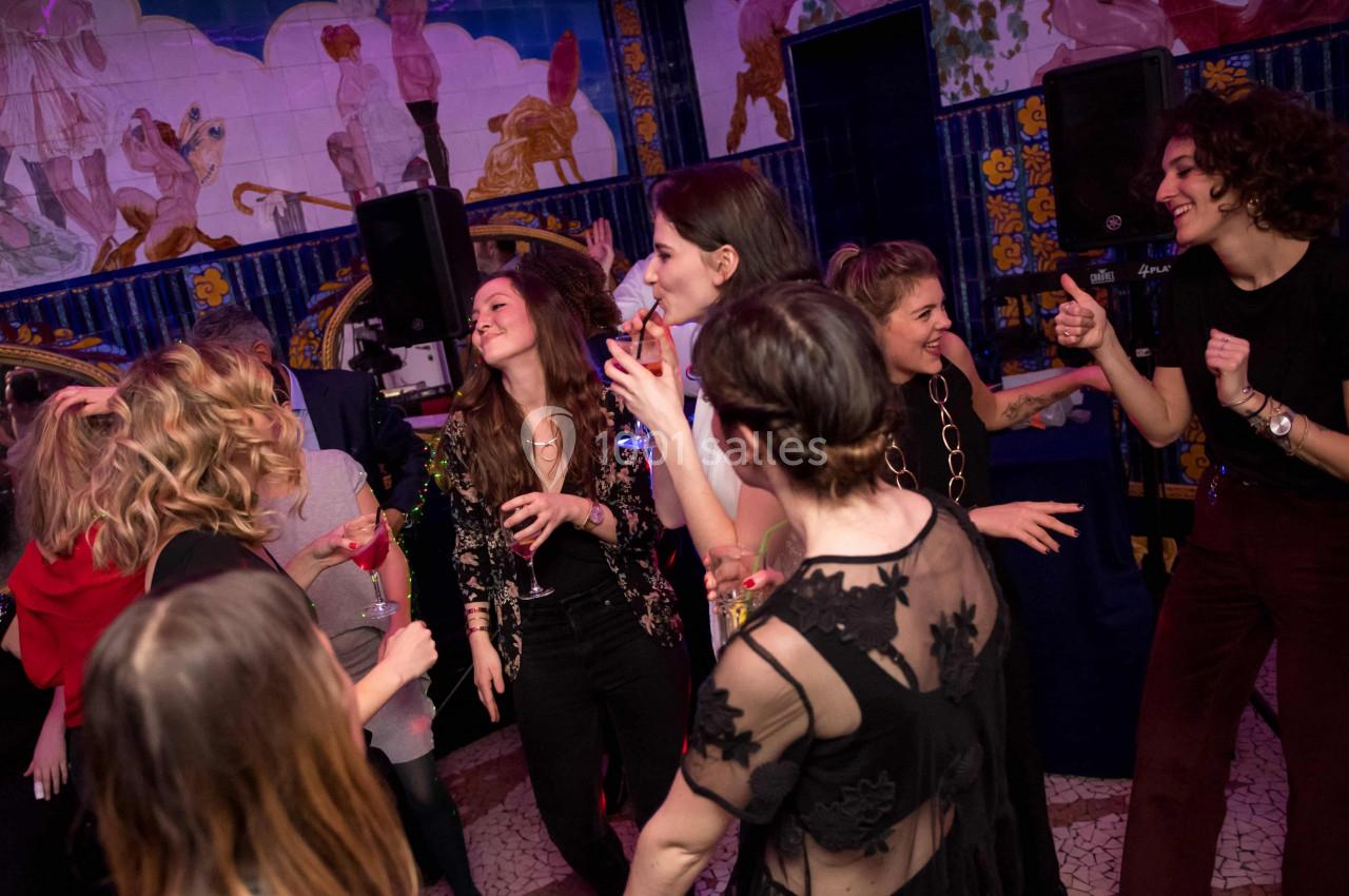 Location salle Paris 2 (Paris) - Aux Belles Poules #16 Des personnes dansent et discutent lors d'une soirée dans un lieu décoré de fresques colorées.