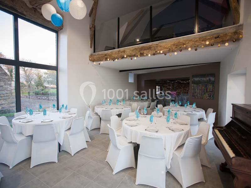 Location salle Plélan-le-Grand (Ille-et-Vilaine) - Domaine Le 5b #11 Salle de réception lumineuse avec tables rondes dressées, chaises blanches, et mezzanine en bois visible en arrière-plan.