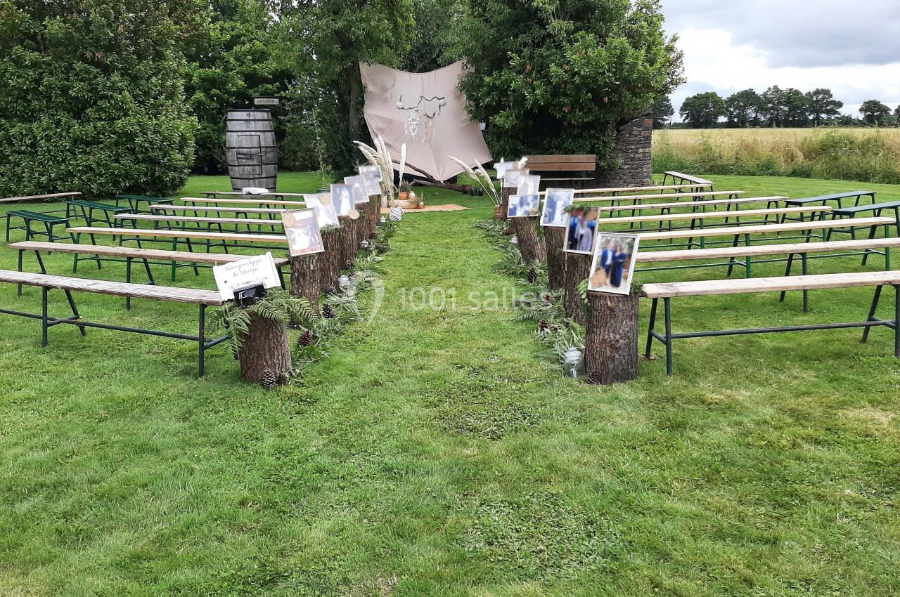 Location salle Plélan-le-Grand (Ille-et-Vilaine) - Domaine Le 5b #17 Allée extérieure bordée de bancs en bois et décorée pour une cérémonie, avec un fond naturel et un décor champêtre.