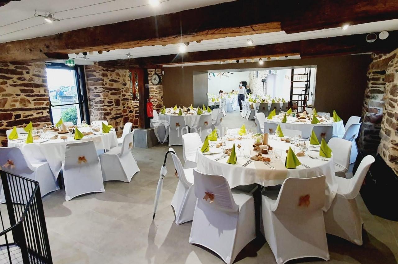 Location salle Plélan-le-Grand (Ille-et-Vilaine) - Domaine Le 5b #14 Salle de réception avec des tables rondes décorées de nappes blanches et serviettes vertes, dans un cadre rustique.