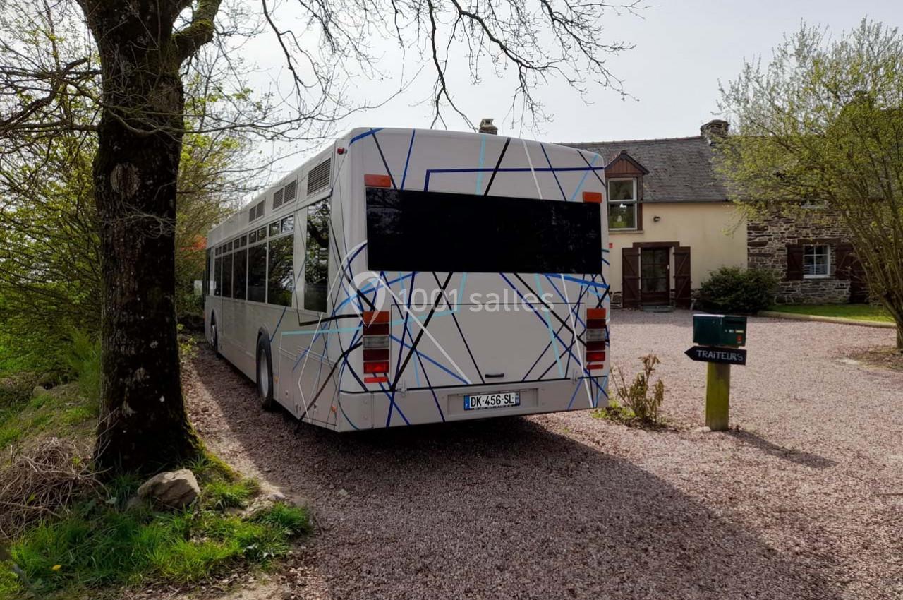 Location salle Plélan-le-Grand (Ille-et-Vilaine) - Domaine Le 5b #38 Autobus blanc stationné sur une allée gravillonnée devant une maison en pierre entourée de verdure.