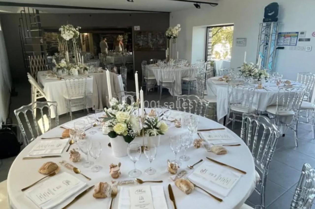 Location salle Plélan-le-Grand (Ille-et-Vilaine) - Domaine Le 5b #52 Salle de réception décorée pour un mariage, avec tables rondes dressées, nappes blanches et compositions florales élégantes.