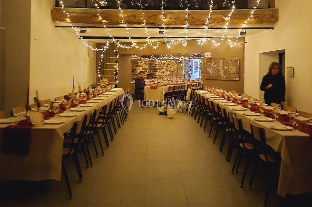 Location salle Plélan-le-Grand (Ille-et-Vilaine) - Domaine Le 5b #58 Salle décorée pour un repas festif, avec longues tables dressées, guirlandes lumineuses suspendues et murs en pierre.
