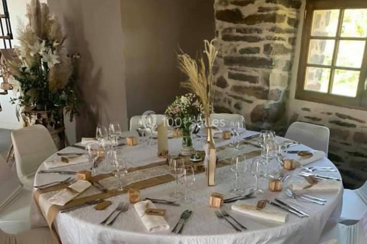 Location salle Plélan-le-Grand (Ille-et-Vilaine) - Domaine Le 5b #59 Table ronde décorée pour un repas, avec nappes blanches, couverts disposés, fleurs et éléments naturels en centre de table.