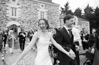 Robe de mariée en dentelle suspendue devant une fenêtre lumineuse avec vue sur un jardin verdoyant.