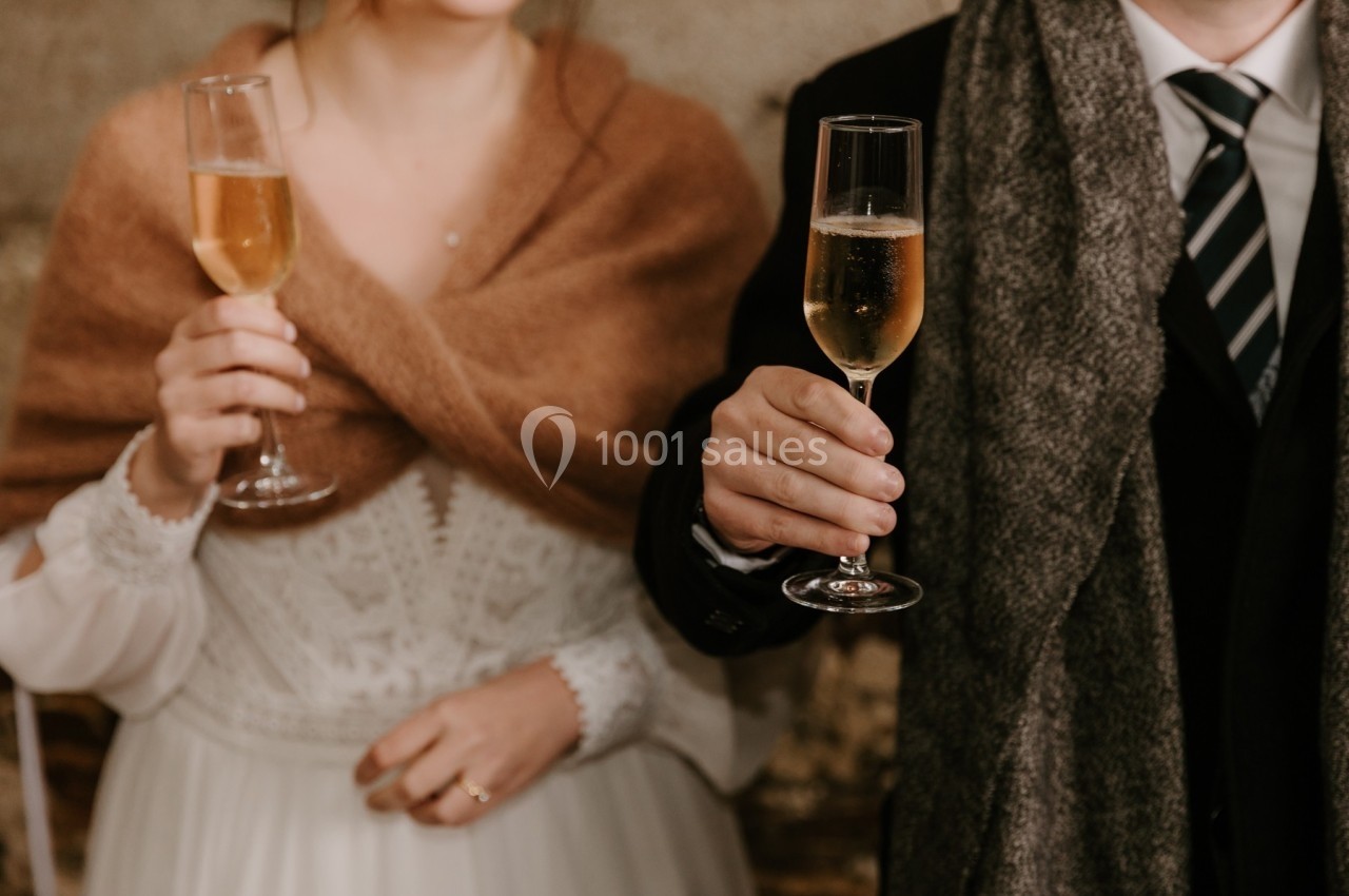 Un couple en tenue élégante tenant des flûtes de champagne dans un cadre chaleureux.