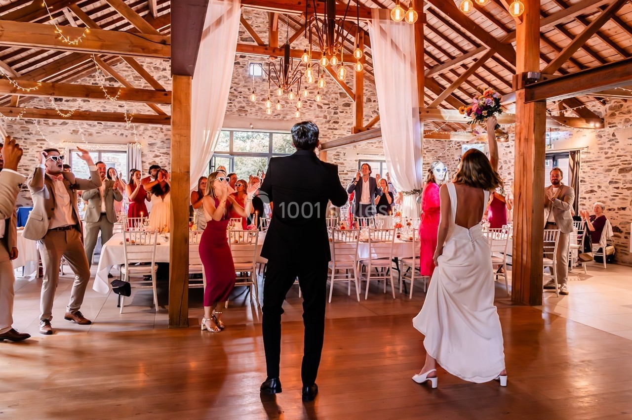 Un couple danse au centre d'une salle de réception décorée, entouré d'invités applaudissant.