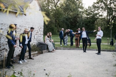Robe de mariée en dentelle suspendue devant une fenêtre lumineuse avec vue sur un jardin verdoyant.