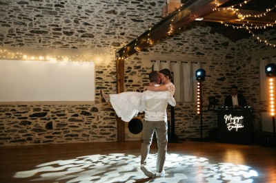 Robe de mariée en dentelle suspendue devant une fenêtre lumineuse avec vue sur un jardin verdoyant.