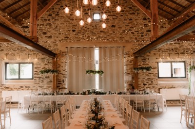Robe de mariée en dentelle suspendue devant une fenêtre lumineuse avec vue sur un jardin verdoyant.