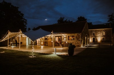 Robe de mariée en dentelle suspendue devant une fenêtre lumineuse avec vue sur un jardin verdoyant.