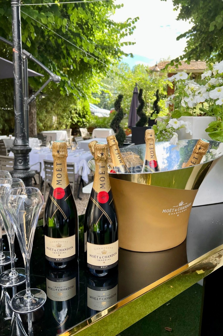 Bouteilles de champagne Moët & Chandon avec flûtes en verre sur une table extérieure, entourée de verdure.