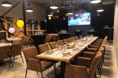 Salle décorée pour un anniversaire avec ballons noirs et dorés, tables dressées et une scène en fond.