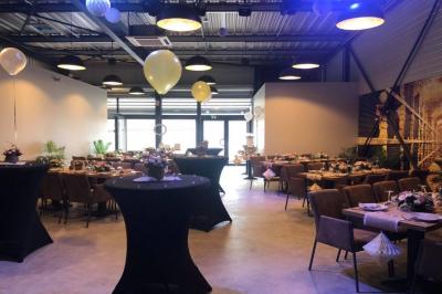 Salle décorée pour un anniversaire avec ballons noirs et dorés, tables dressées et une scène en fond.