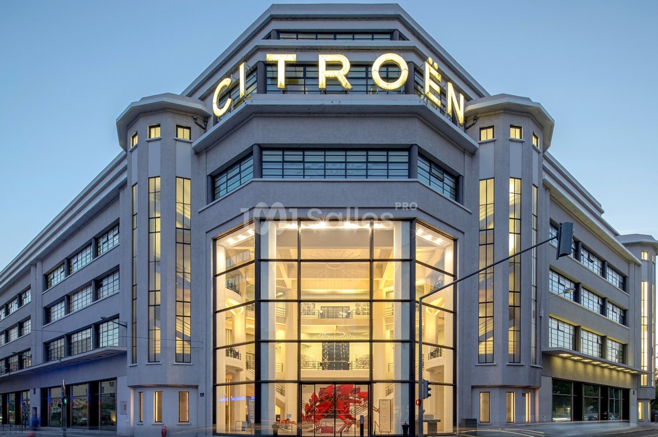 Bâtiment moderne avec façade vitrée et enseigne lumineuse ’Citroën’, éclairé en fin de journée.