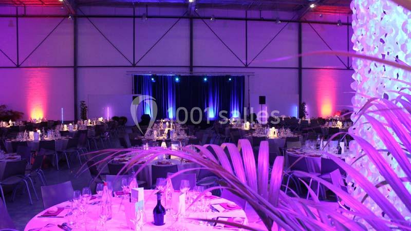 Location salle Dammarie-les-Lys (Seine-et-Marne) - Espace Pierre Bachelet #4 Salle de réception décorée avec des éclairages violets, tables dressées et scène éclairée en arrière-plan.
