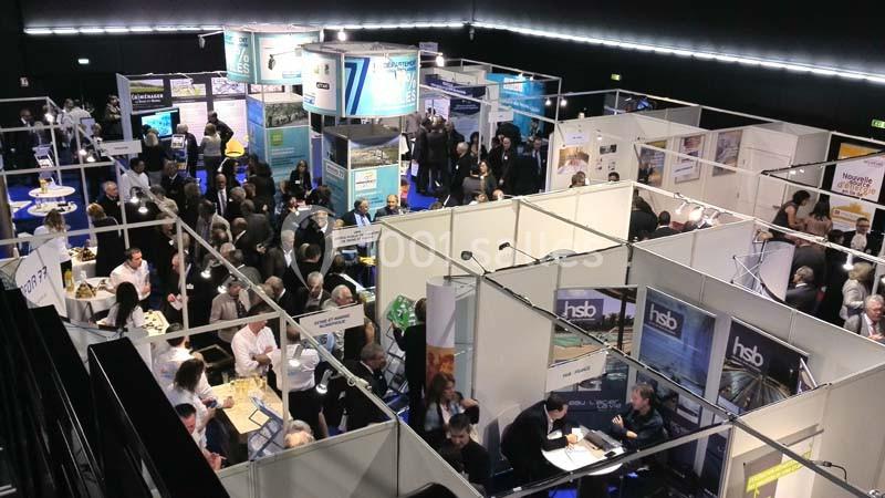 Location salle Dammarie-les-Lys (Seine-et-Marne) - Espace Pierre Bachelet #19 Vue aérienne d'un salon professionnel avec des stands, des visiteurs et des échanges entre participants.