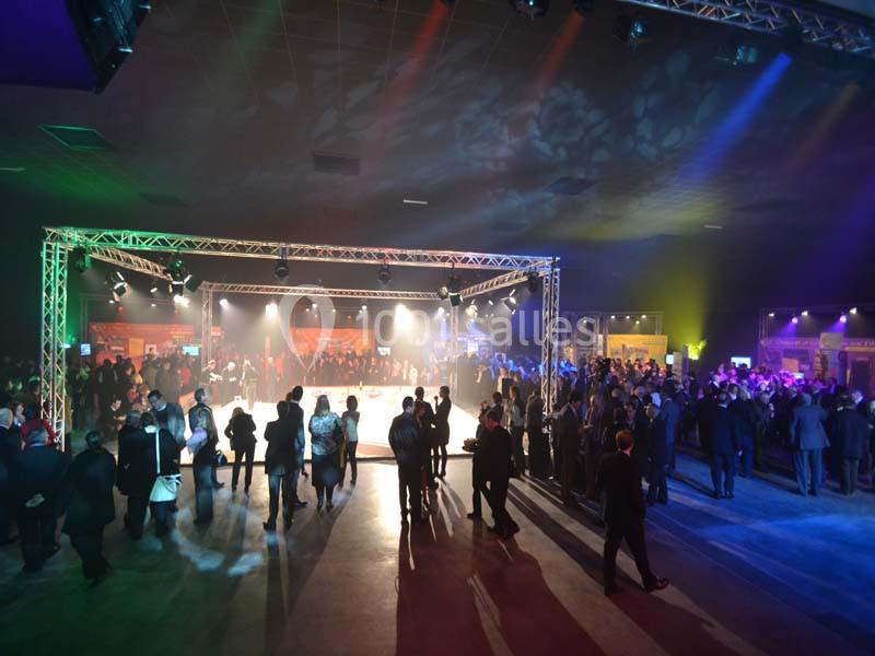 Location salle Dammarie-les-Lys (Seine-et-Marne) - Espace Pierre Bachelet #14 Salle de réception éclairée avec des projecteurs colorés, des invités rassemblés autour d'une piste centrale.