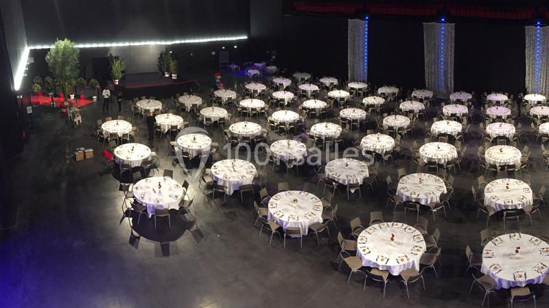 Location salle Dammarie-les-Lys (Seine-et-Marne) - Espace Pierre Bachelet #7 Salle de réception avec de nombreuses tables rondes dressées pour un événement, éclairage tamisé et décor sobre.