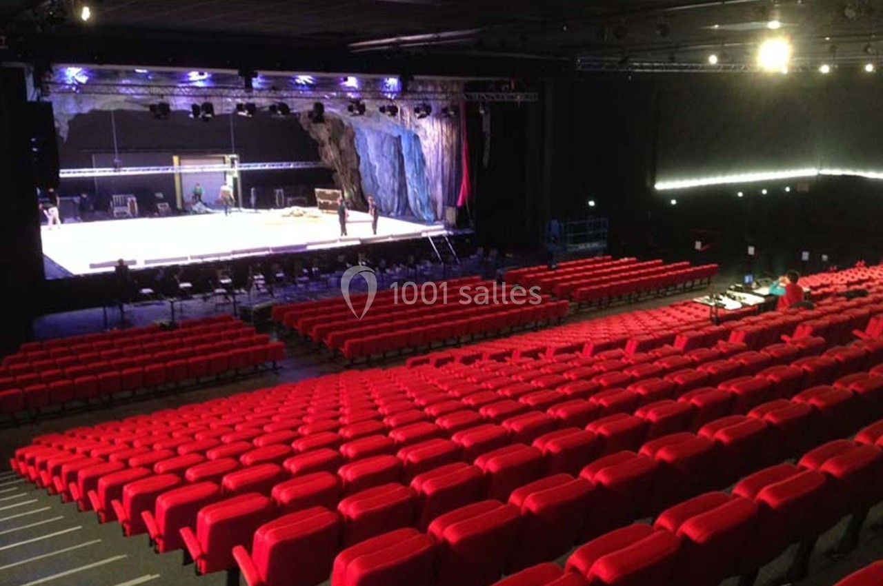 Location salle Dammarie-les-Lys (Seine-et-Marne) - Espace Pierre Bachelet #9 Salle de spectacle avec rangées de sièges rouges vides et une scène en préparation sous des éclairages.